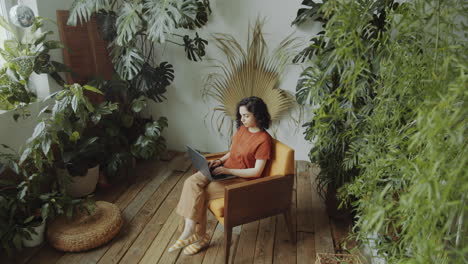 biracial girl working on laptop in room with plants