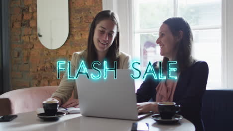 animation of flash sale text over diverse businesswomen using laptop