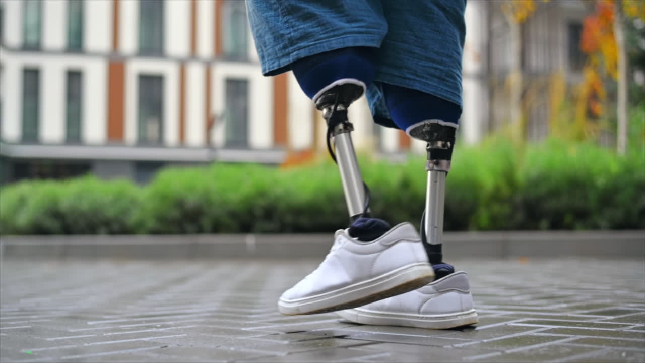 View of a walking man with prosthetic legs and white sneakers at rainy weather, greenery on the background