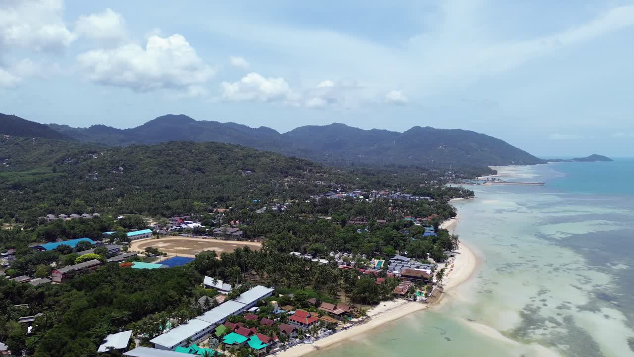 Aerial footage of Thong Sala Beach with a wide sandy shoreline, turquoise sea and lush tropical scenery on Koh Phangan island, Thailand