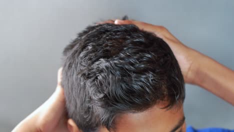 teenage boy scratching head against black background