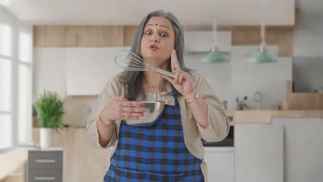 Happy-Indian-aged-housewife-talking-to-someone-while-making-food