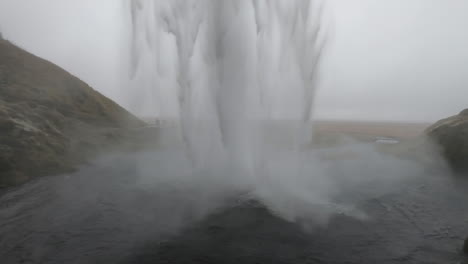 冰島瀑布 seljalandsfoss 的後面,有一位女士欣賞著瀑布的美麗和力量