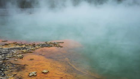 Hermosos-Colores-De-La-Costa-Y-El-Lago-Con-Vapor-Volador-Sobre-La-Superficie-En-El-área-Hidrotermal-De-Wai-o-tapu,-Nz