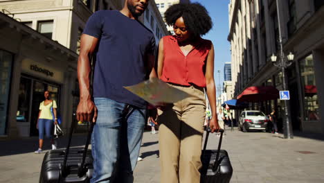 a couple navigating a city street with suitcases and a map