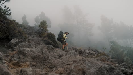 man with backpack and trekking poles climbing on acatenango volcano hike in guatemala, central america