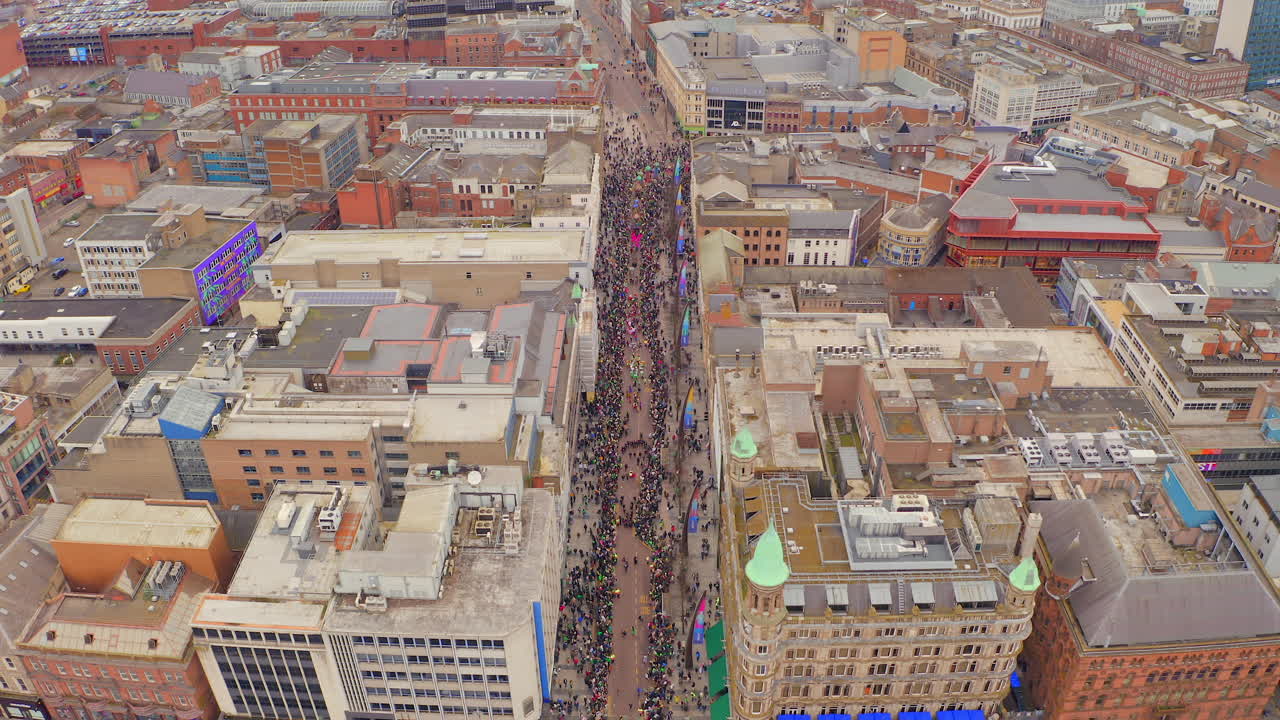 Static high-angle drone shot of Belfast St. Patrick's parade floats surrounded by packed crowds