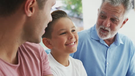 multi-generation male hispanic family talking and laughing on sofa at home together
