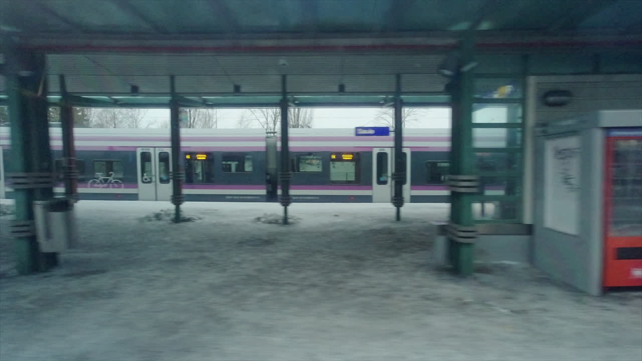 헬싱키 대중교통 열차가 겨울 눈 속에서 역 플랫폼을 떠납니다.