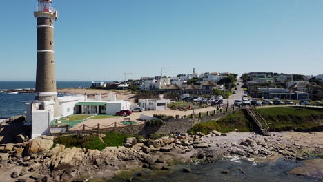 drone ascending revealing lighthouse on rocks with lagoon in foreground