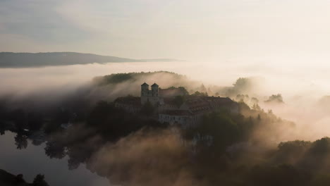 aerial drone view of benedictine abbey over vistula river in tyniec in the morning fog, krakow, poland