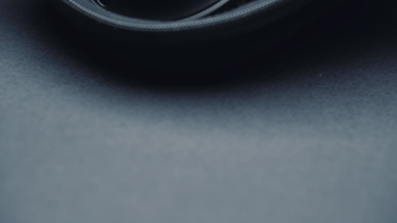 A product shot of black headphones on a black background, In a box. Camera movement  up from bottom, close-up.