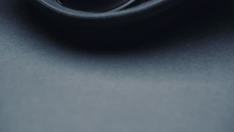 a product shot of black headphones on a black background, in a box. camera movement  up from bottom, close-up.
