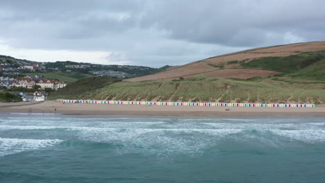 sideways aerial shot of beach huts on a golden sandy beach at sunset