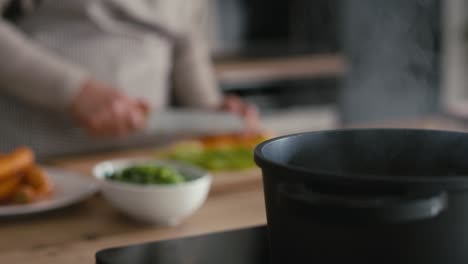 Detail-of-water-boiling-in-the-pot-and-unrecognizable-woman-cooking-in-the-background