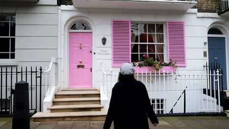 Female-tourist-poses-in-front-of-Fourteen-Trevor-Square,-lovely-pink-house