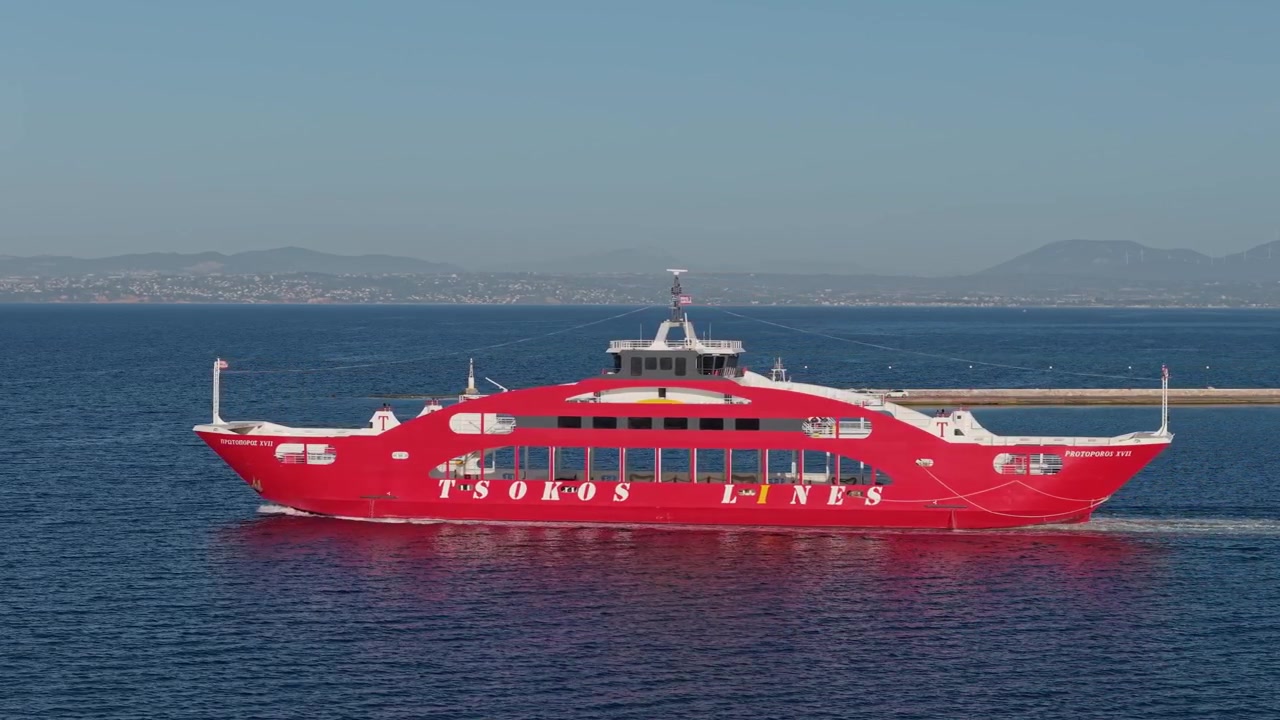 Statiske optagelser af Eretria Havn, der viser en rød færge, der sejler ud over det rolige vand i den Sydlige Euboeiske Golf, hvilket illustrerer daglig kysttransport i Grækenland.