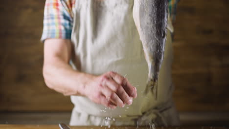 Person-removes-salt-from-herring-on-wooden-background