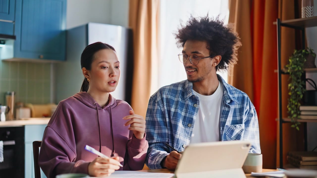 Couple studying home kitchen. Closeup multiethnic pair doing homework together.