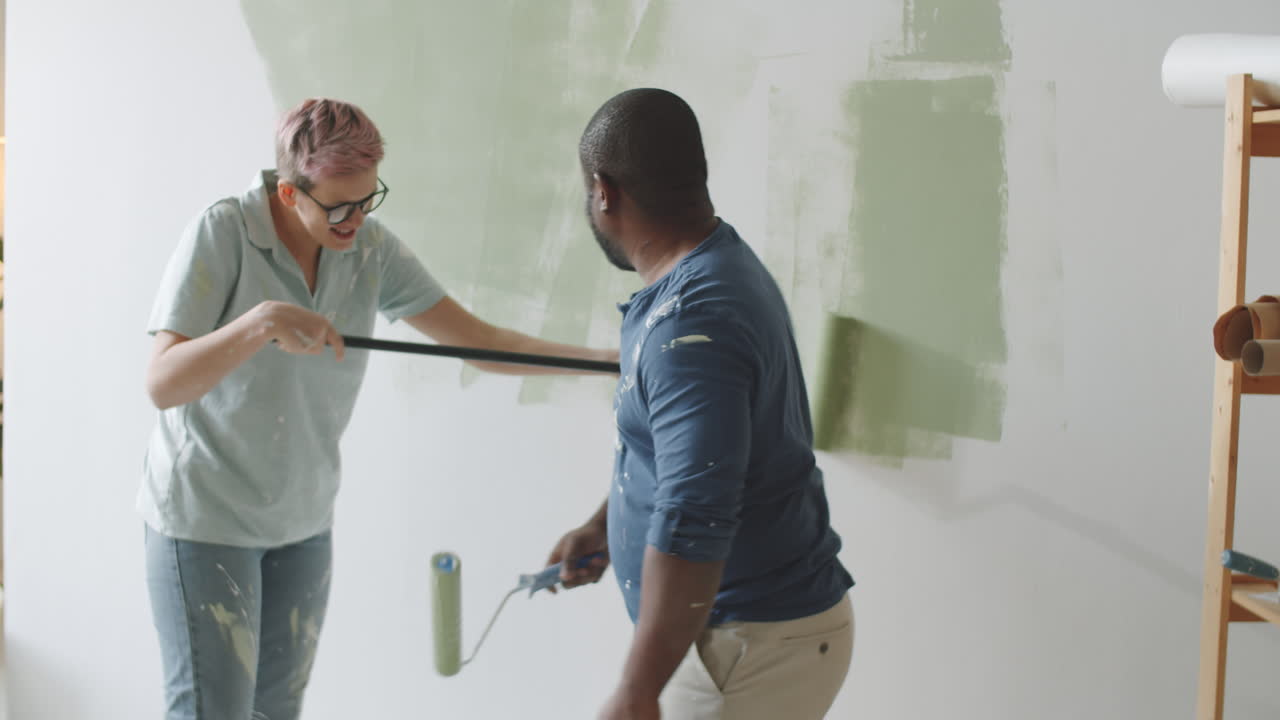 una pareja pintando una pared.