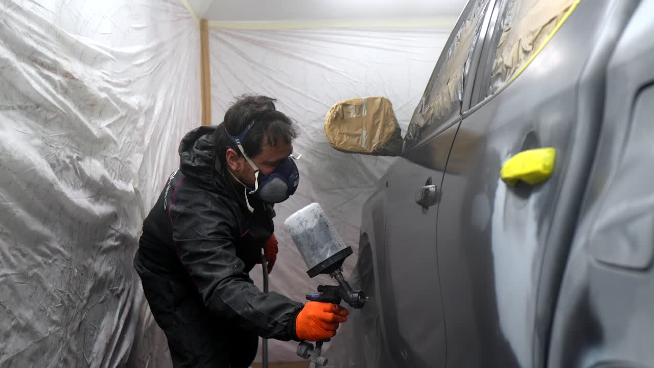 Man Spray Painting Car in Auto Repair Shop