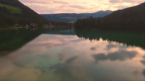 drone forward shot of big lake dobbiaco at dusk in toblacher see, south tyrol, italy