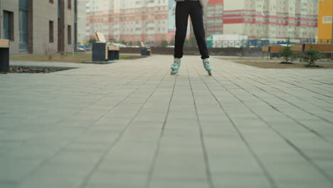 close-up shot capturing the smooth motion of rollerblades gliding in a park. the person wearing black trousers is captured mid-movement, emphasizing the flow and motion of the activity