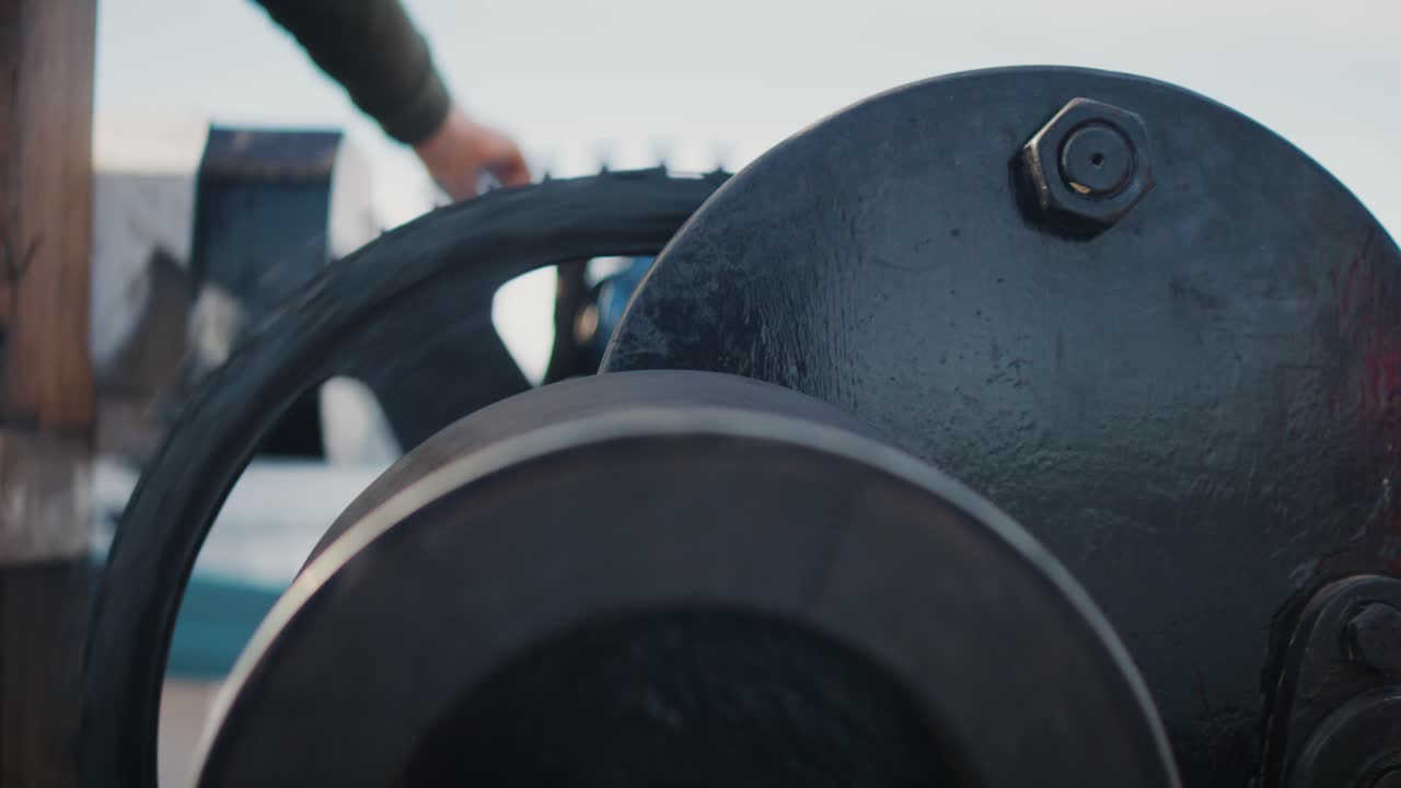 Close-up of anchor chain being hauled aboard boat, rusty metal links on windlass, maritime operation and nautical equipment detail, strength and reliability concept