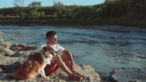 junger mann und sein hund am ufer des flusses