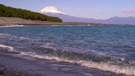 Vista-De-ángulo-Bajo-De-Las-Olas-Rompiendo-En-La-Playa-Con-El-Telón-De-Fondo-Del-Monte-Fuji-En-Un-Día-Claro