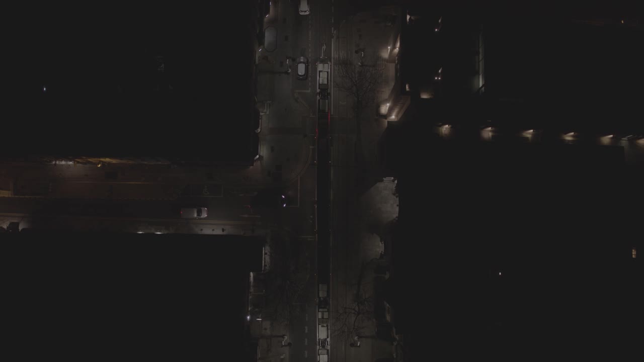 A flyover tracking shot that follows the Luas, an Irish Tram as it follows through the dark night time Dawson Street of Dublin, Ireland. The streets are only lit by the steet lights around it.
