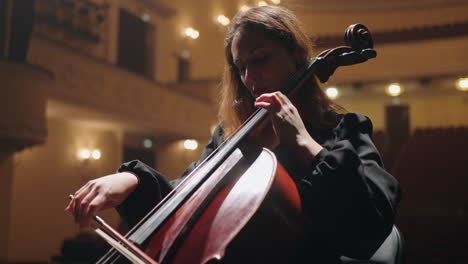 romantic woman is playing violoncello in music hall female cellist is rehearsing on scene of philharmonic hall