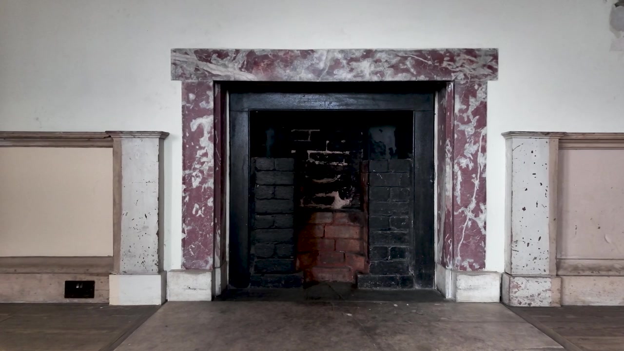 Vista dettagliata di un vecchio camino in fase di ristrutturazione, che mostra l'intricato processo di restauro di un interno domestico classico.