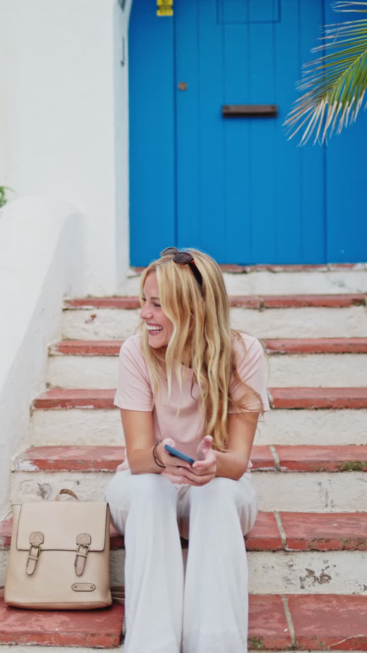 Giovane donna felice seduta sulle scale e che usa lo smartphone