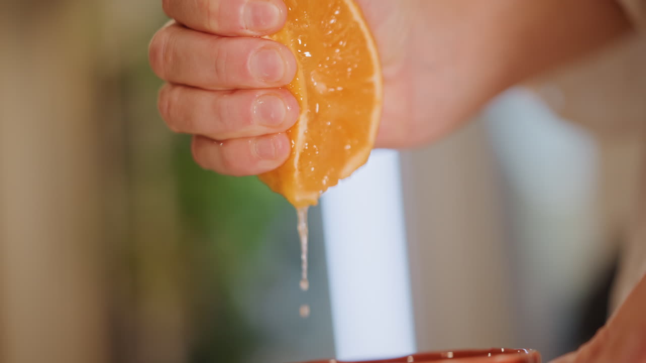 Exprimiendo naranja en una taza para un refrescante inicio matutino. Capturando el acto de exprimir naranja para un comienzo saludable. Primer plano de una mano exprimiendo un gajo de naranja sobre una taza para la preparación de un desayuno nutritivo.