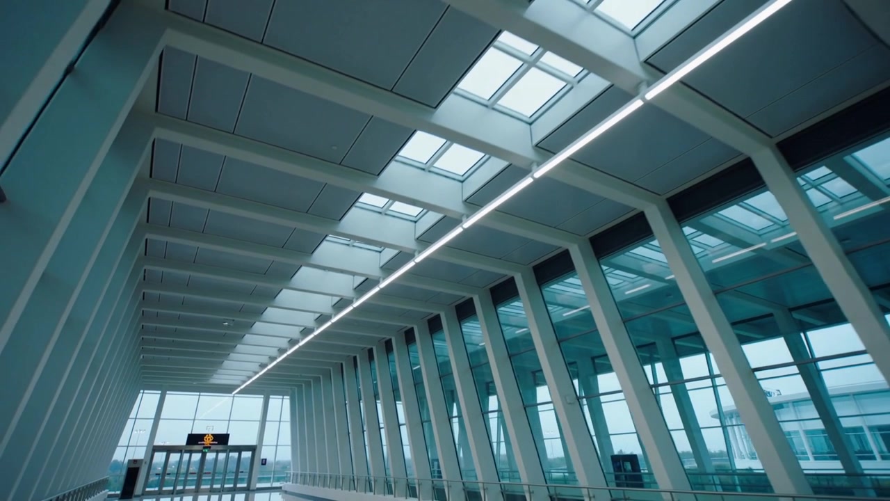 La telecamera inizia a inclinarsi verso l'alto e a muoversi in avanti al terminal, mostrando un lucernario, LED e colonne.