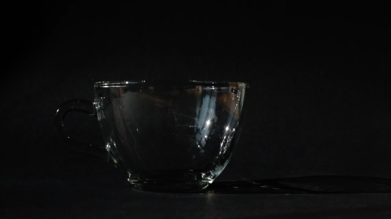 Pouring hot coffee in a cup on a black background