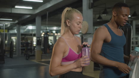 side view of caucasian female monitor and an athletic african american man in the gym.