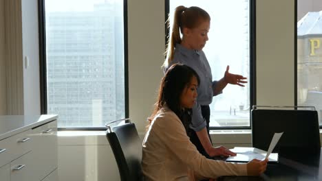 Two-businesswomen-discussing-over-digital-tablet-in-office-4k