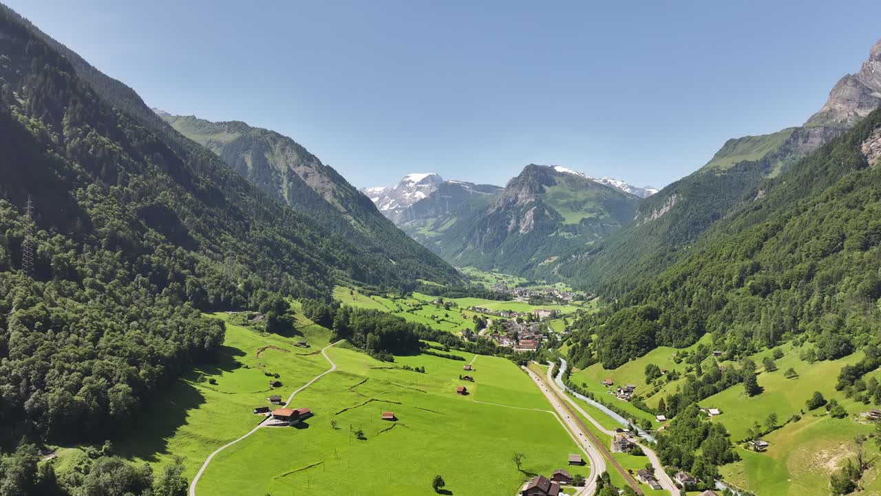 Aerial view of Betschwanden in Glarus Süd, Switzerland, with green alpine valley, scattered chalets, and the majestic Tödi mountain in the background