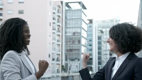 successful businesswomen giving high five on street