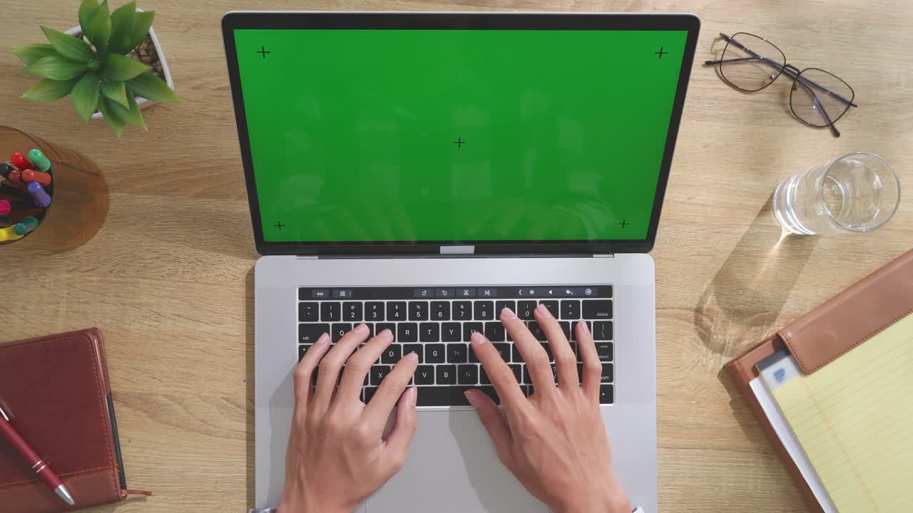 Person Typing on Laptop with Green Screen