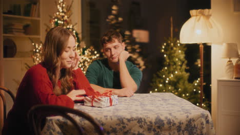 man giving christmas gift to female friend at home