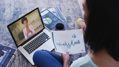 African-american-woman-holding-a-document-having-a-video-call-with-female-colleague-on-laptop