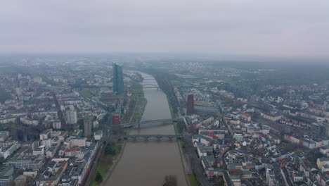 Los-Delanteros-Vuelan-Por-Encima-De-La-Gran-Ciudad.-Varios-Puentes-Que-Cruzan-El-Río.-Vista-Aérea-Panorámica-Nebulosa-De-Los-Barrios-Urbanos.-Fráncfort-Del-Meno,-Alemania