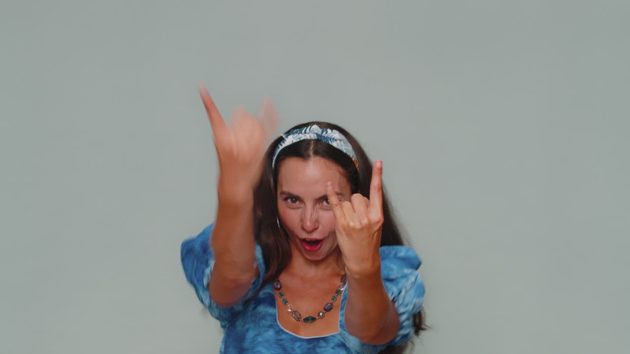 Donna graziosa felicissima che mostra il gesto del rock and roll, balla, esultando emotivamente per il successo