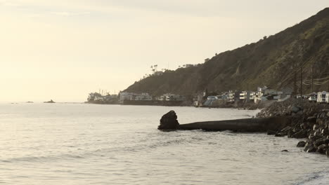 calm rocky shoreline with waves hitting the edge, next to the road of big rock beach malibu