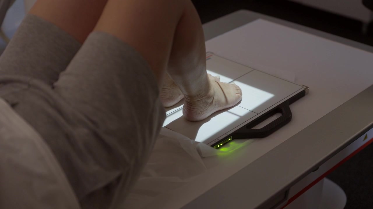 Close up of a patients feet on a digital radiography sensor plate during a medical examination in a clinic or hospital setting.