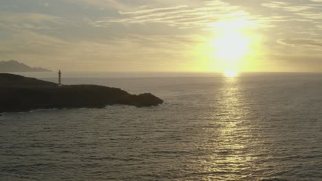 drone disparó panorama de un faro a la hora dorada con el océano y el sol