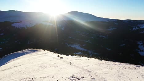 a solo hiker walking on snowy hill with snowshoes